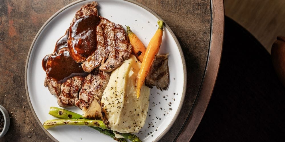 Steak dinner with mashed potatoes, asparagus, and carrots.