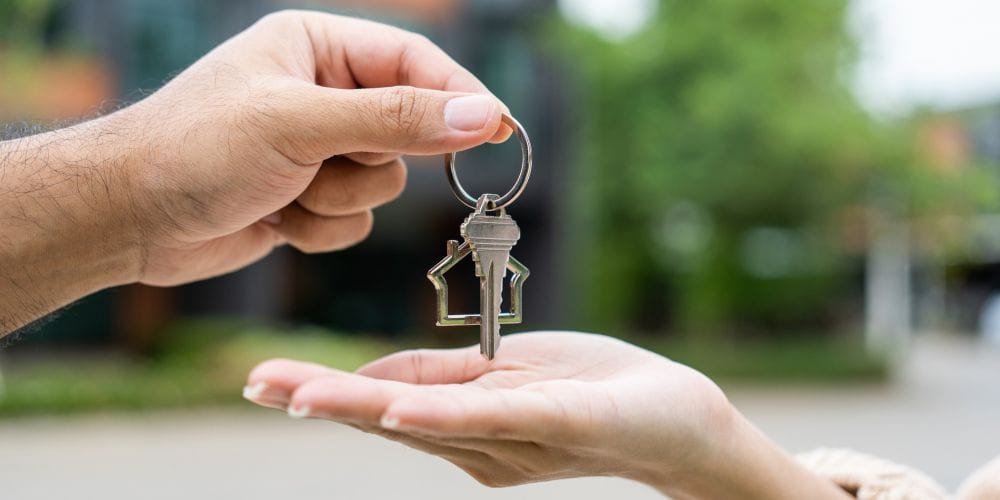 Man handing the keys to a vacation rental to a woman taking a relaxing vacation.