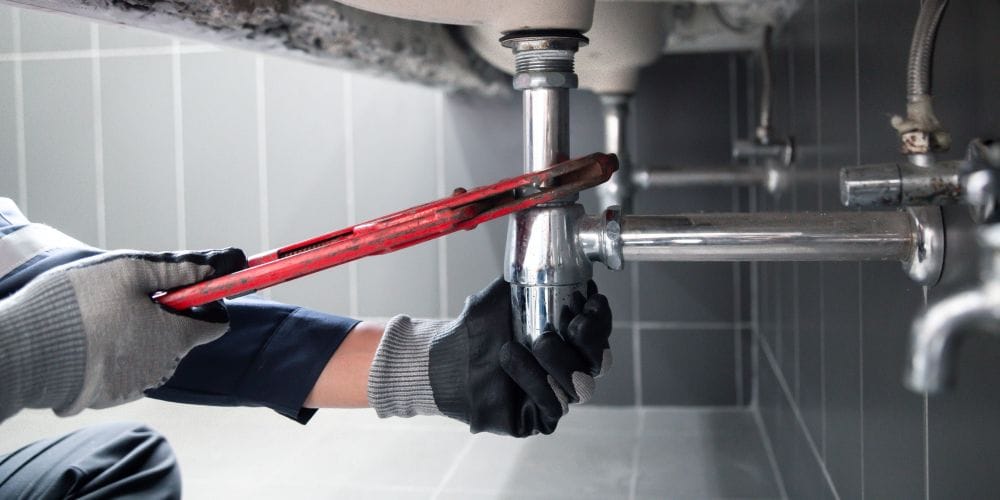 Plumber fixing leaky pipe.